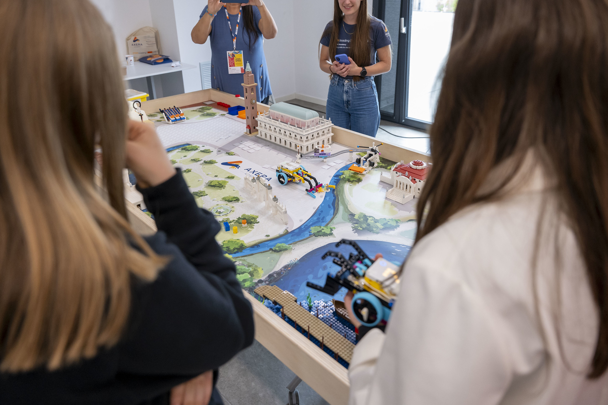 Bambini e ragazze partecipano a un’attività creativa e interattiva di TEDxVicenza Adventure 2025, costruendo con mattoncini LEGO un paesaggio urbano con edifici, strade, fiume e veicoli.