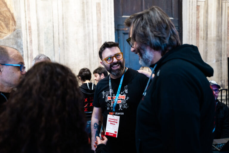 Persone del team TEDxVicenza riunite e impegnate in una conversazione durante il backstage di un evento.
